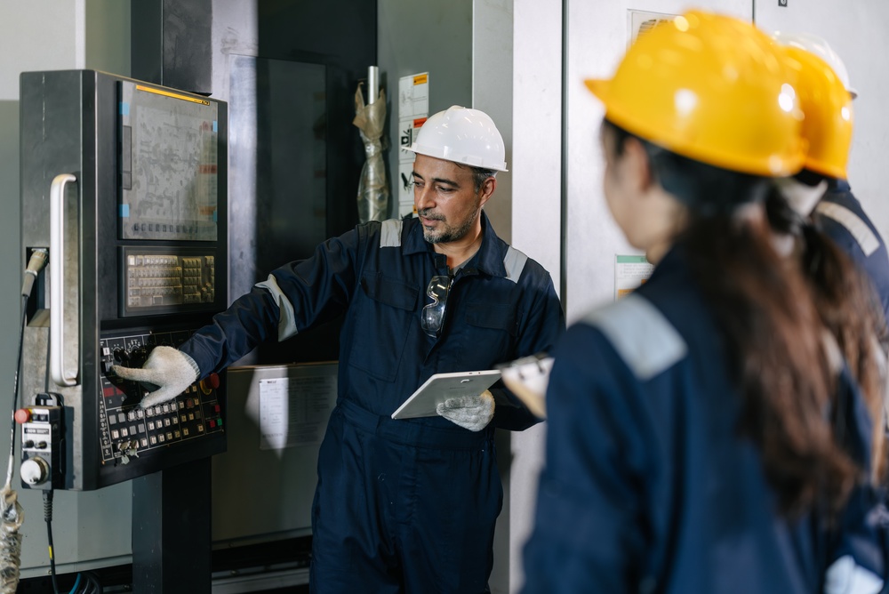 Trainer briefing industrial professionals at a machine control panel